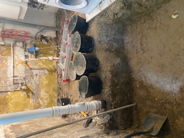 Spande med jord bæres op fra kælder