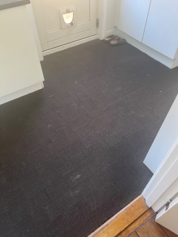 Et løst gulvtæppe under spisebord og et fast gulvtæppe i enter. Tæpperne skal renses