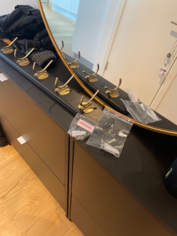 Ophæng af knagerække (L: 60 cm) og rundt spejl (ø 80 cm) i betonvæg i entréen.