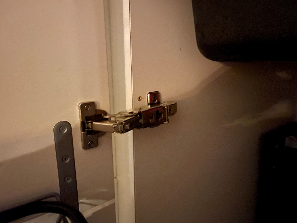 En køkkenlåge der hænger, og som delvist er faldet af pga. hængsler der er rykket ud af skabet