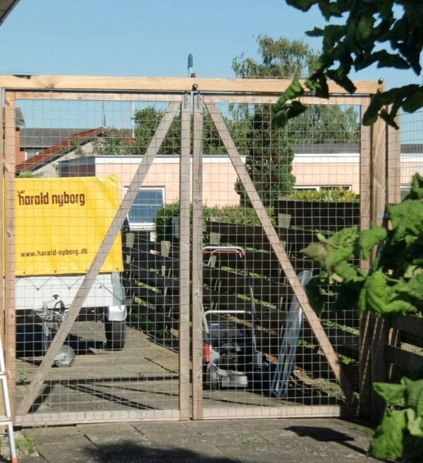 Katteindhegning af have med trådhegn og stolper langs hækken samt et hegn med låge