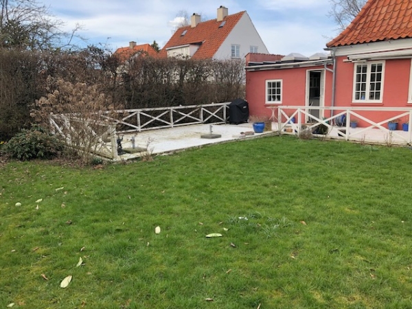 En lang hvidmalet træterrasse med gelænder