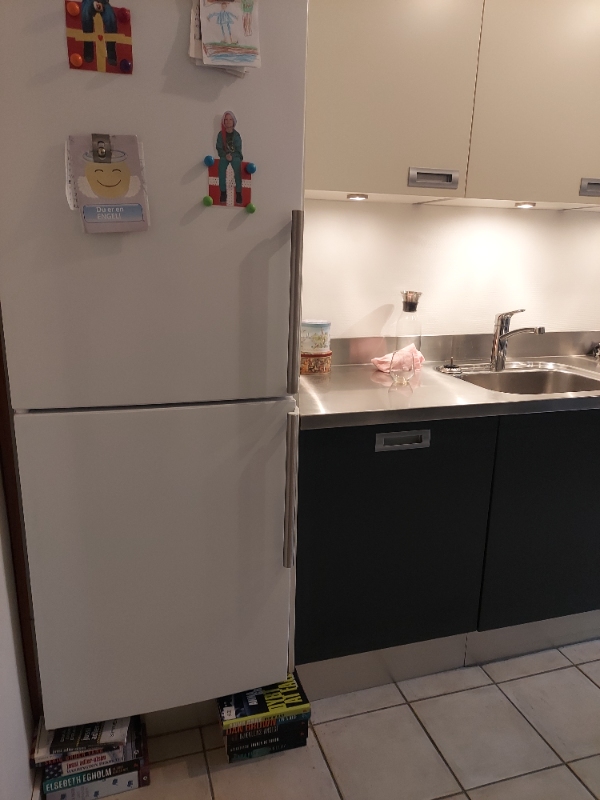 Flytte køle/fryseskab ud af skab. Fjerne bund i skab, så køle/fryseskab kan stå på gulvet.