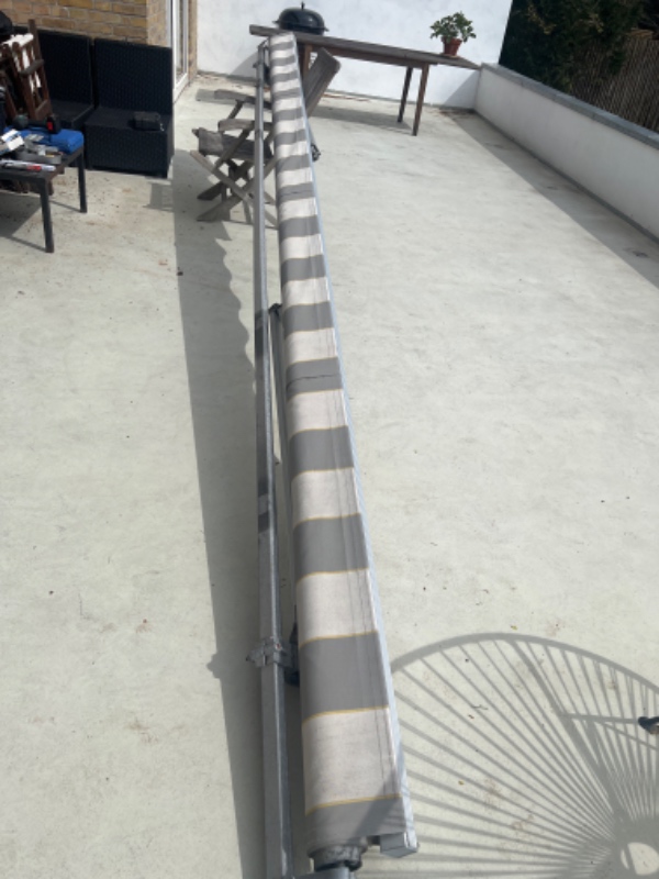 Opsætning af markise på underside af altan. Altan består af beton og metal gitter.