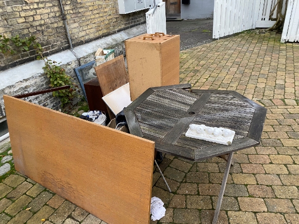 1-2 m3 affald, primært træmøbler samt et kølefryseskab (ca. 1,90 m), der skal fjernes fra baggård.