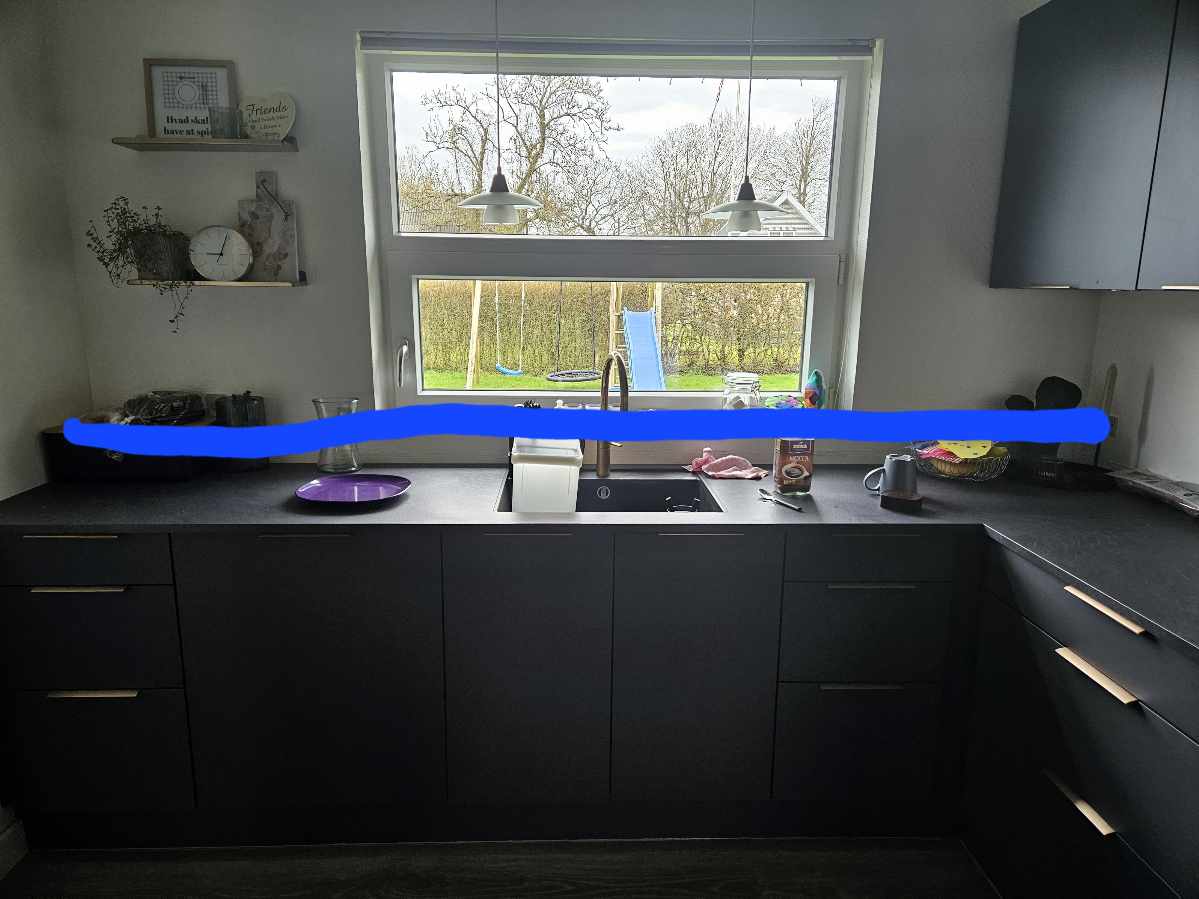 Sætte fliser op i køkken langs væg.