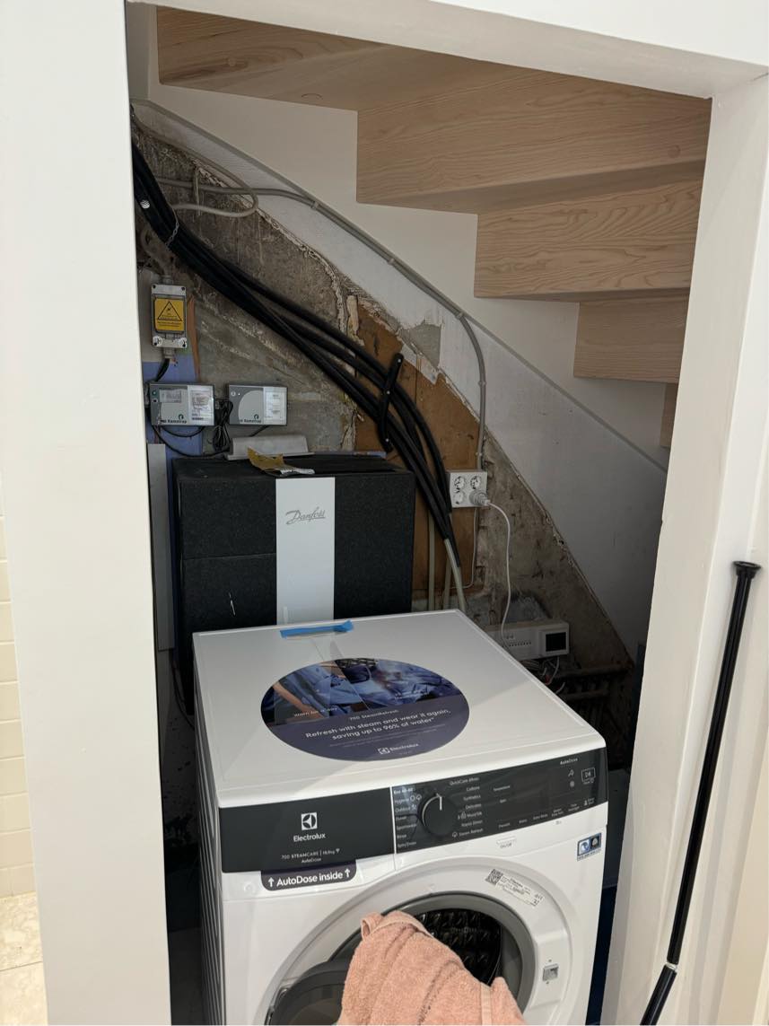 Væg under trappe, der lukker ind til badeværelse og skjuler installationer. Det er lidt svært at forklare.