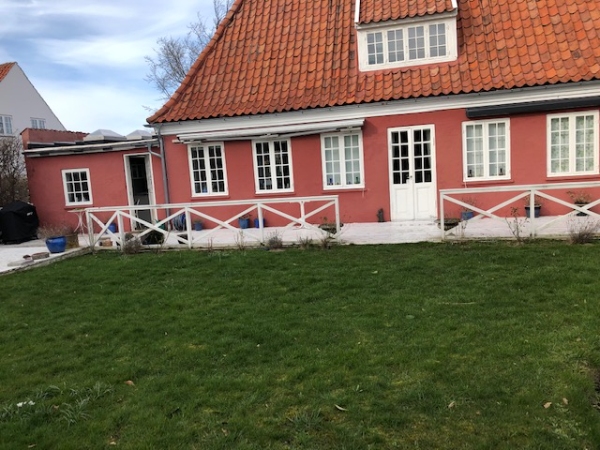 En lang hvidmalet træterrasse med gelænder