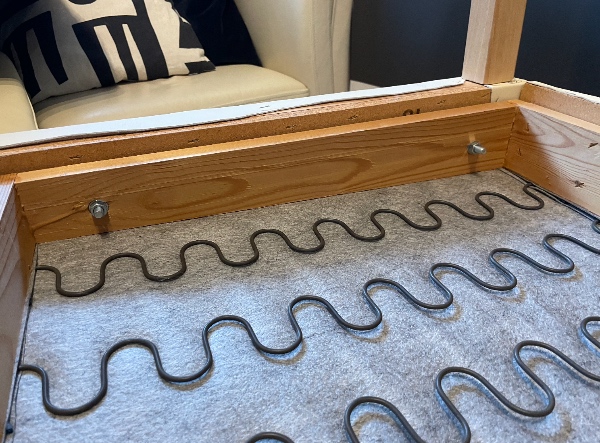 En sofa hvor træet i bunden har givet efter og er gået i stykker