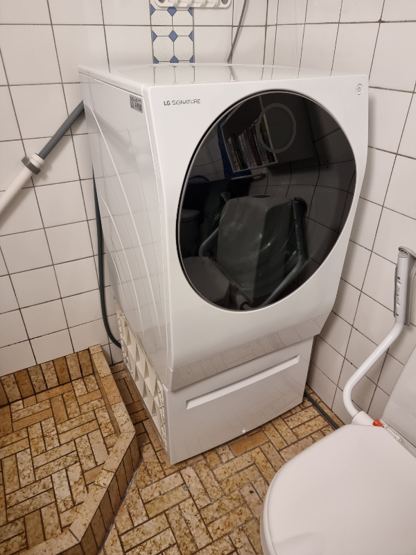 Løfte 90 kg vaskemaskine op, fjerne underskuffe, påsætte stilleben, dreje 90 grader og ned på gulv.