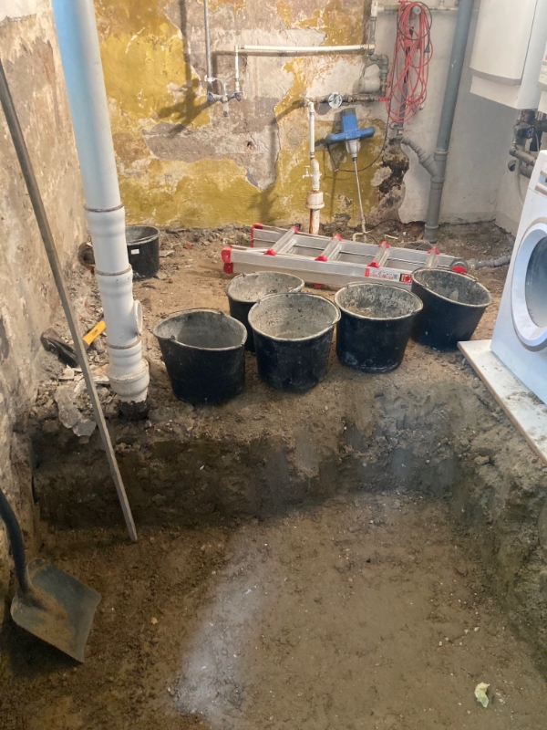 Spande med jord bæres op fra kælder