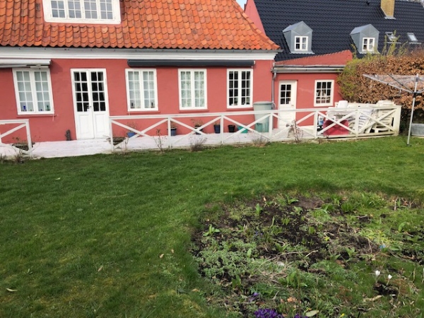En lang hvidmalet træterrasse med gelænder