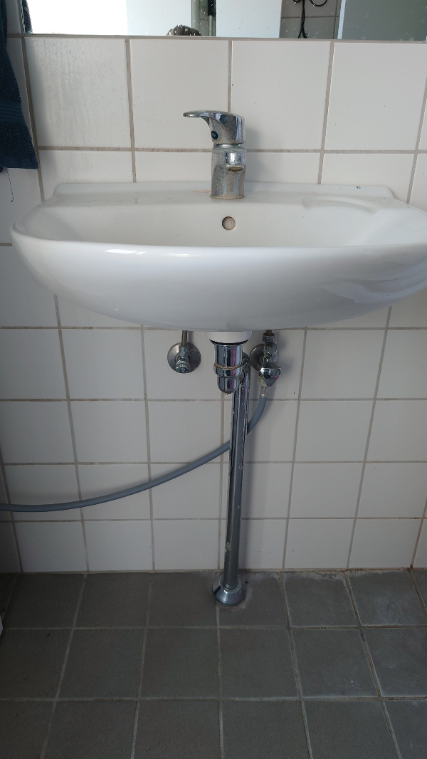 Afmundteret gammel håndvask på badeværelset.  Munteret ny håndvask med underskab