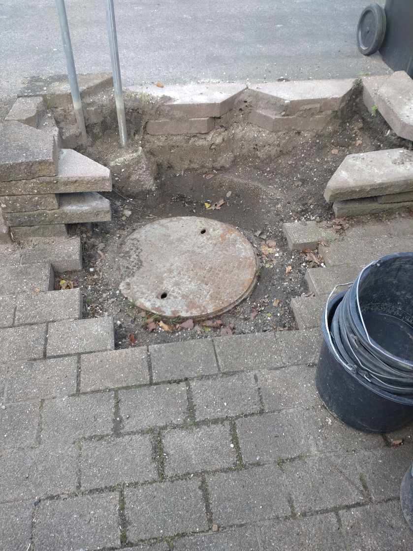 Løftet 2 kloakdæksler og få fliserne til at se ok ud igen. Det må gerne være så skraldespanden kan stå bedre.